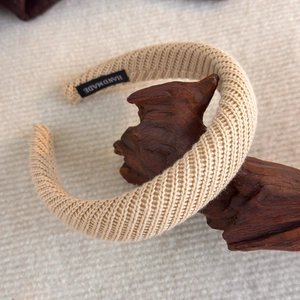 Detail eines handgefertigten Rippstrick Stirnbandes in Beige auf Holzständer