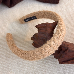 Detail eines hellbraunen Plüsch Stirnbandes mit Hand Made Webetikett auf Holz