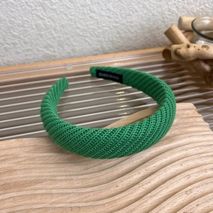 Dettaglio fascia in maglia verde con etichetta fatta a mano su base di legno