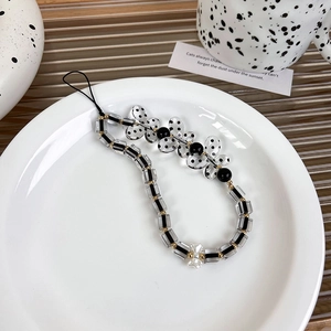 Detail of black and white beaded phone strap with stripe and polka dot patterns
