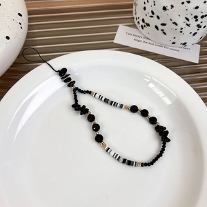 Close-up of black beaded phone strap with resin charms and chic monochrome aesthetic