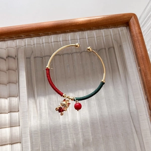 Golden open bangle with red cord wrap, lucky cat pendant, and red bead for New Year