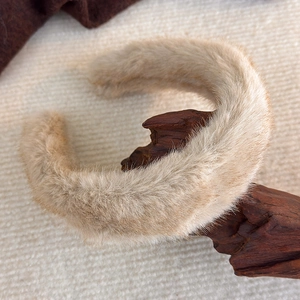 Nahaufnahme des beigen Plüsch-Stirnbands aus Kunstpelz auf Holz für den Herbst-Stil