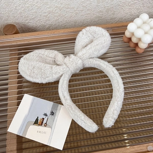 Close-up of cream plush rabbit ear headband on a decorative tray with soft fur texture