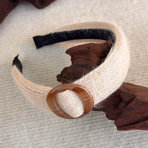 Detailansicht von cremefarbenem Strickstirnband mit bernsteinfarbenem Harzring