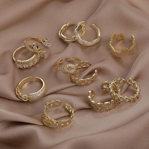 Détail d'un ensemble de 8 bagues dorées avec zircon sur un tissu en satin marron