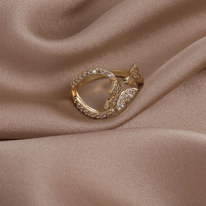 Detail shot of golden butterfly ring with sparkling white zircon on champagne silk cloth