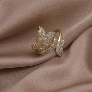 Macro shot of three golden butterfly rings with zircon inlay on brown silk fabric