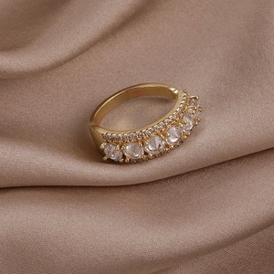 Détail macro d'une bague dorée avec cinq zircons ronds sur fond de soie premium