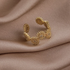 Macro d'une bague dorée en zircon au design d'engrenage sur soie champagne