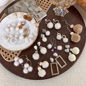 Collection de boucles d'oreilles boules en peluche marron sur plateau vintage