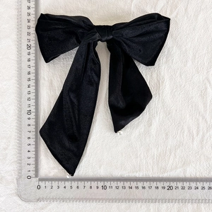 Detailed measurement of large black velvet bow hair clip with pearls on white fabric