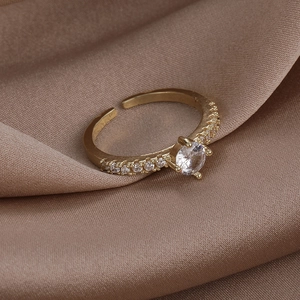 Macro shot of a gold open ring with a large zircon and micro-paved side stones on silk