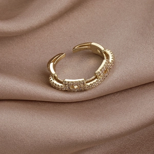 Vue détaillée d'une bague ajustable en or avec zircon sur un élégant tissu en soie champagne