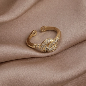 Gros plan d'une bague nœud dorée avec zircons étincelants sur satin de champagne