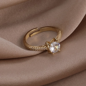 Macro side view of golden cat-ear prong ring with large zircon on champagne silk fabric