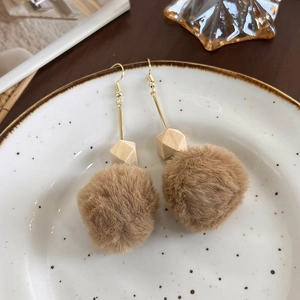 Vue détaillée de boucles d'oreilles d'automne avec pompons marron et perles de bois naturel
