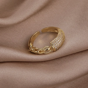 Macro d'une bague ajustable en chaîne cubaine dorée et zircons sur soie champagne