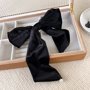 Detail of a large black velvet bow hair clip with white pearl charms in a jewelry box