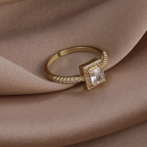 Detailed macro view of a gold-tone halo ring with a large rectangular zircon on silk