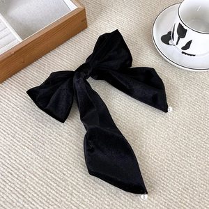 French vintage black velvet hair clip with elegant pearl charms on a beige background