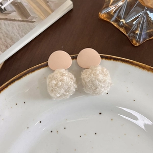 Gros plan de boucles d'oreilles d'hiver avec boules de poils blancs et clous ronds roses