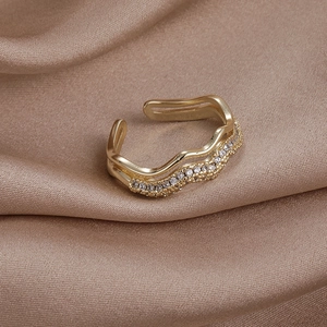 Détail d'une bague vague double couche dorée avec zircons sur satin marron