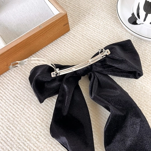 Macro detail of a black velvet bow hair clip with a sturdy silver metal spring fastener