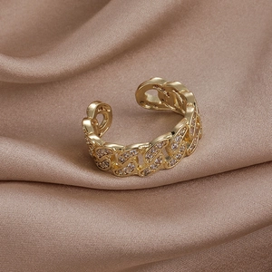Gros plan d'une bague chaîne dorée avec zircons sertis sur du satin couleur champagne