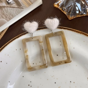 Détail de boucles d'oreilles cœur en peluche avec breloques résine ambre marbré