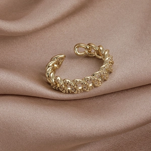 Gros plan sur bague gourmette dorée sertie de zircons sur tissu de soie champagne