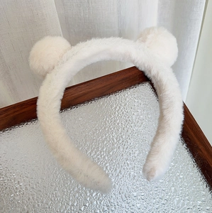 Détail d'un serre-tête en peluche blanche avec oreilles d'ours sur plateau bois