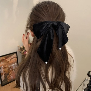 French style black velvet bow hair clip with white pearl accents on long curly hair
