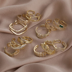 Set di anelli geometrici in oro con zirconi su sfondo di raso color champagne di lusso