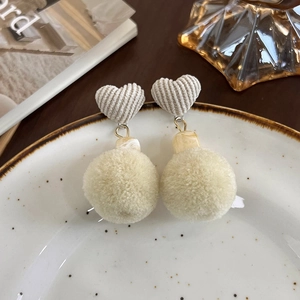 Détail de boucles d'oreilles cœur vintage avec pompon et texture velours côtelé