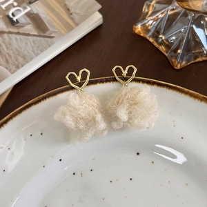 Vue détaillée des clous d'oreilles cœur dorés avec pompons en fausse fourrure blanche