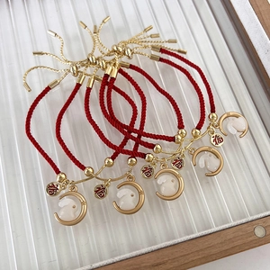 Detail van rode geweven armbanden met gouden konijnenhangers en Chinese Fu-karakters