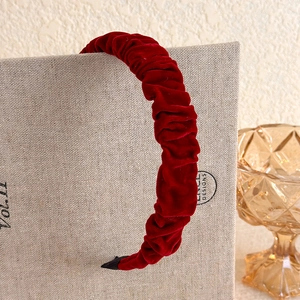 Close-up of pleated velvet headband in deep burgundy with soft texture and protective tips
