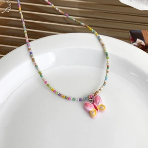 Collier de perles colorées avec un pendentif papillon rose pour un style estival tendance