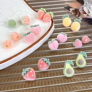 Detail view of assorted flocked fruit stud earrings with soft matte velvet texture
