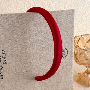 Close-up of vintage burgundy plush headband resting on a grey linen textured book