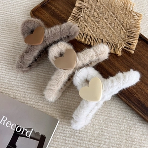 Detailsicht auf Plüsch-Haarklammern mit Herz in Grau, Beige und Weiß auf Holztablett