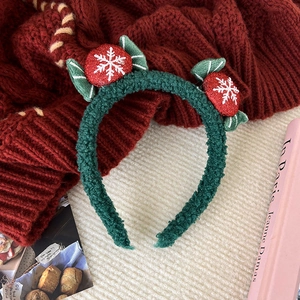 Detailed view of plush green Christmas headband with red glitter berries and snow pattern
