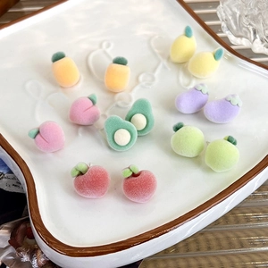Detailed view of colorful flocked fruit earrings on a white ceramic tray display