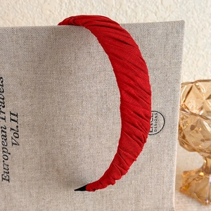 Detail of vintage burgundy pleated velvet headband with textured fabric on book cover