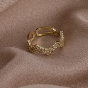 Dettaglio macro dell'anello a doppia fascia dorata con zirconi incastonati su seta marrone