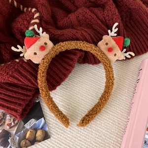Detail of Christmas headband with plush reindeer dolls, red hats and golden antlers