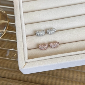 Close-up of pavé bean earrings in silver and rose gold finish on velvet tray