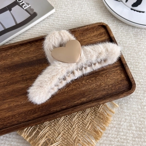 Detail der beige Plüsch-Haarklammer mit khakifarbenem Herz auf rustikalem Holztablett