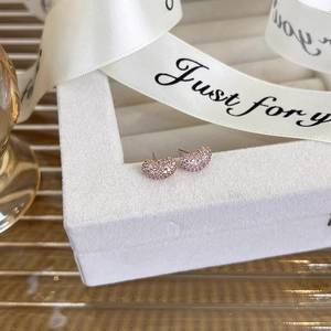 Close-up of rose gold bean-shaped earrings with micro-pave cubic zirconia on a gift box